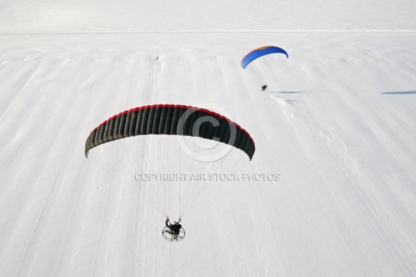 Parapentes motorisés survolant un champ plein de neige vu du ci
