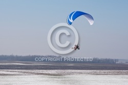 Aerial view of paramotor flying over the vastness of winter snow