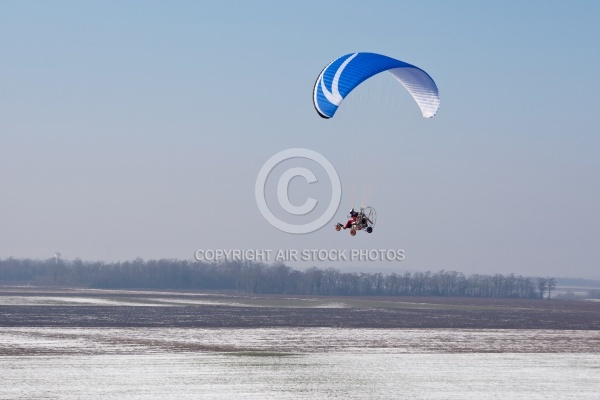 Aerial view of paramotor flying over the vastness of winter snow
