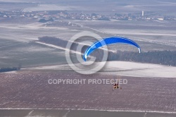 Motor paraglider flying in winter in a snow-white landscape seen