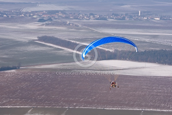 Motor paraglider flying in winter in a snow-white landscape seen