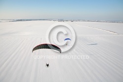 Paramoteur survolant un champ enneigé en hiver vu du ciel