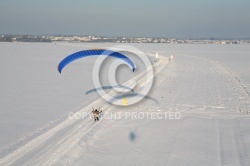 Parapente motorisé suivant une route enneigée avec un panneau