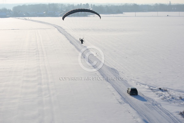 Vue aérienne du parapente motorisé survolant une route enneig